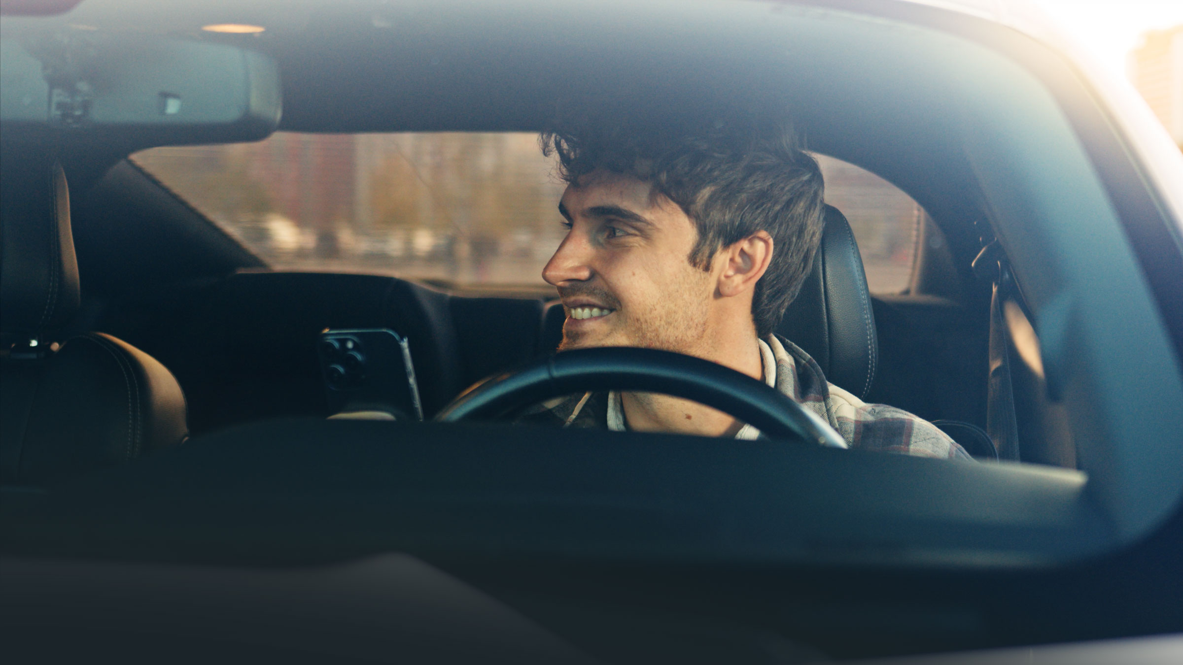 Happy man with a cup of coffee smiling in his car